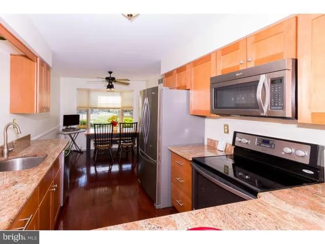 a kitchen with stainless steel appliances kitchen island granite countertop a stove refrigerator and sink