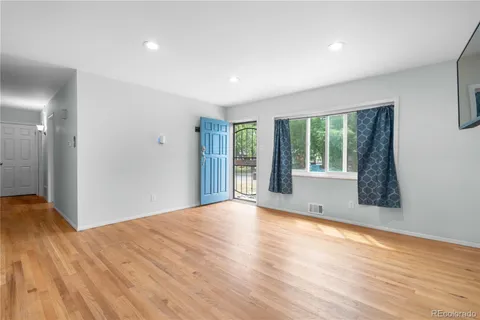 a view of an empty room with wooden floor and a window