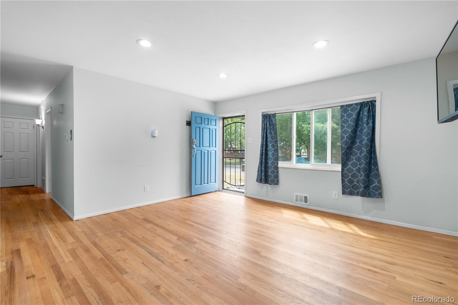 6572 Kipling Street Arvada, CO 80004 - Photo 5 of 18 a view of an empty room with wooden floor and a window
