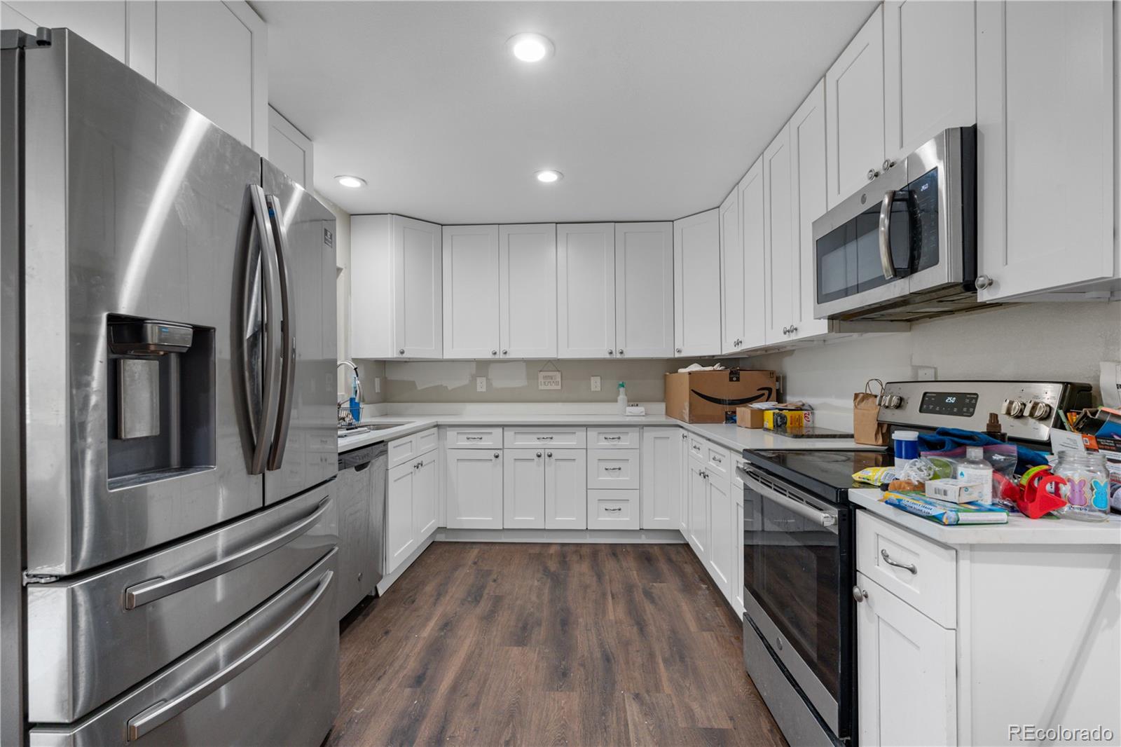 6572 Kipling Street Arvada, CO 80004 - Photo 6 of 18 a kitchen with stainless steel appliances granite countertop a refrigerator microwave and sink
