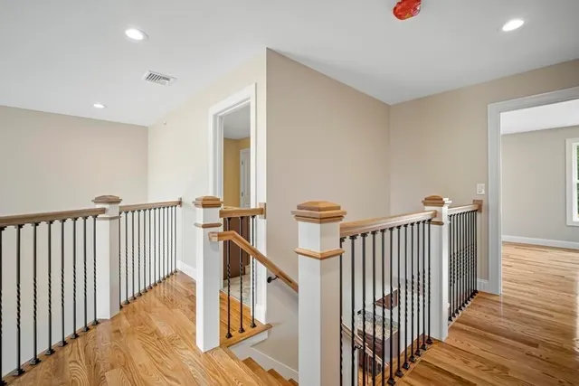 a view of a hallway with wooden floor and stairs