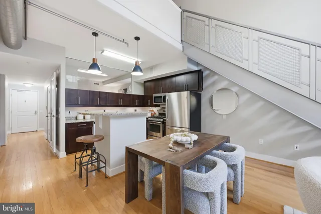 a kitchen with stainless steel appliances kitchen island granite countertop a table chairs and a refrigerator