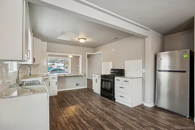 a kitchen with a refrigerator stove top oven and sink