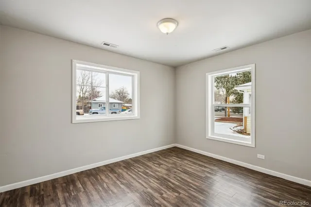 a view of an empty room with window and wooden floor