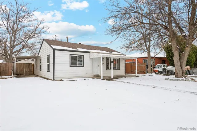 a front view of a house with a road covered in snow