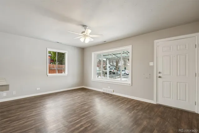 a view of an empty room with a window and wooden floor
