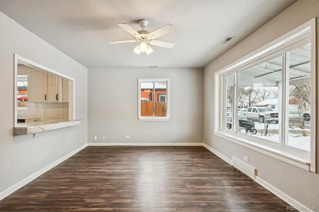 a view of an empty room with a window and wooden floor