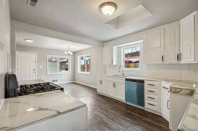 a kitchen with granite countertop a sink stove and cabinets