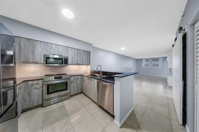 a kitchen with stainless steel appliances granite countertop a stove top oven a sink dishwasher and a refrigerator
