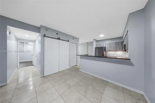 a view of a kitchen with refrigerator and white cabinets