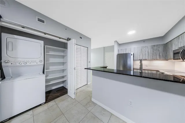 a view of a kitchen with refrigerator and white cabinets