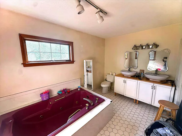 a spacious bathroom with a tub sink and wooden floor