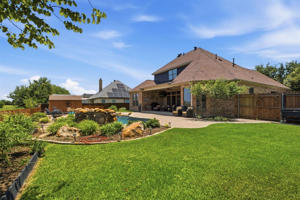 600 Aspen Street Pilot Point, TX 76258 - Photo 2 of 39 Expansive backyard featuring a manicured lawn, a swimming pool with rock landscaping, and a covered patio