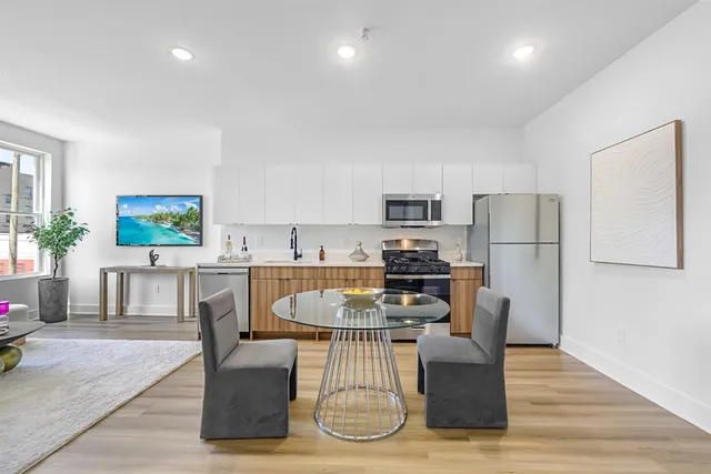 a living room with furniture a kitchen view and a refrigerator