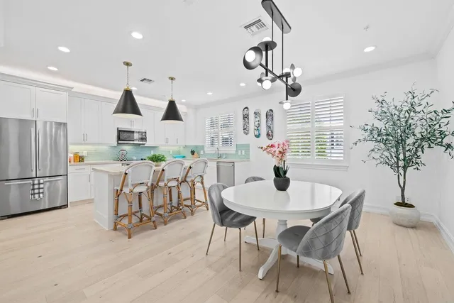 a kitchen with stainless steel appliances a dining table chairs and chandelier