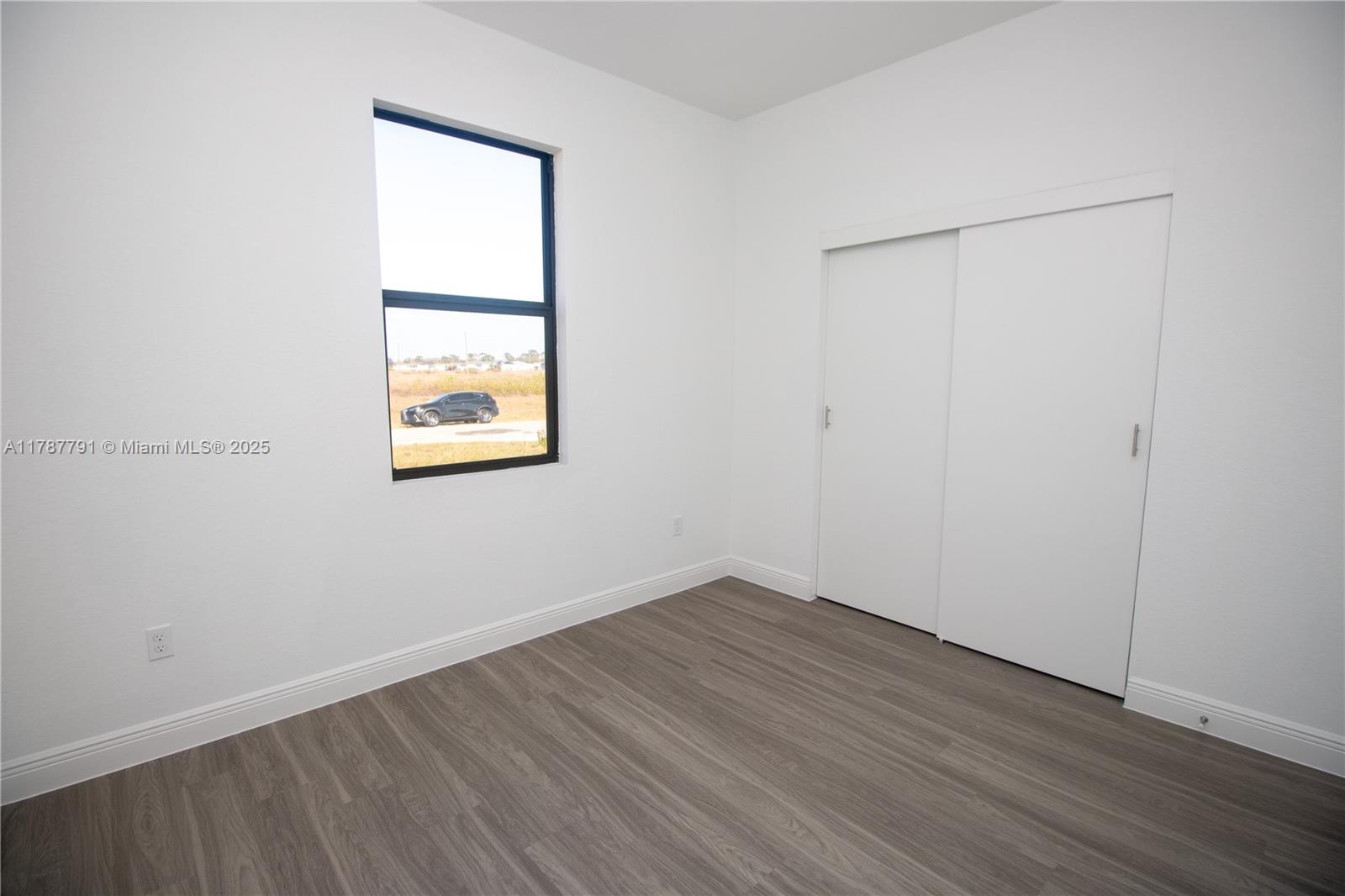 9023 Meadow Circle LaBelle, FL 33935 - Photo 21 of 35 an empty room with wooden floor and windows