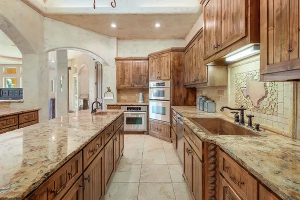 a large kitchen with stainless steel appliances granite countertop a sink and cabinets