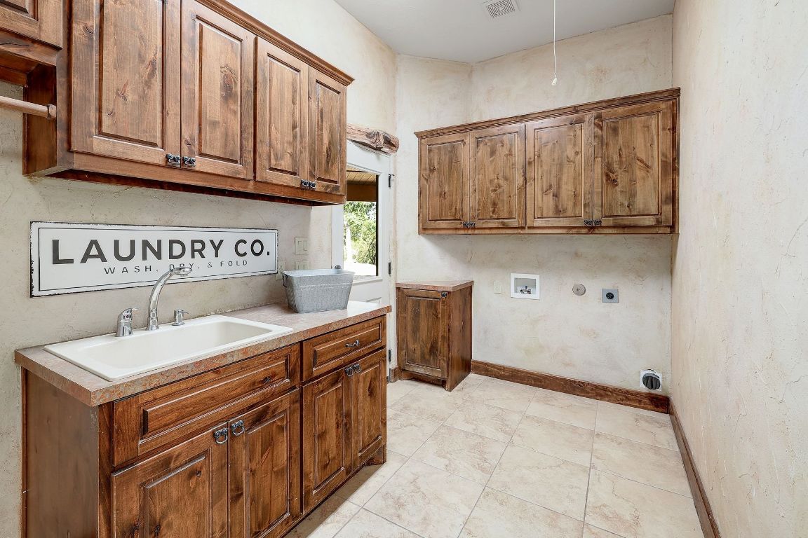 1120 Redbird Road Granger, TX 76530 - Photo 23 of 40 Laundry area featuring cabinet space, washer hookup, hookup for an electric dryer, & light tile patterned flooring