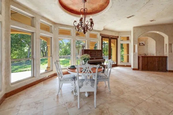 a view of a dining room with furniture a chandelier and large windows