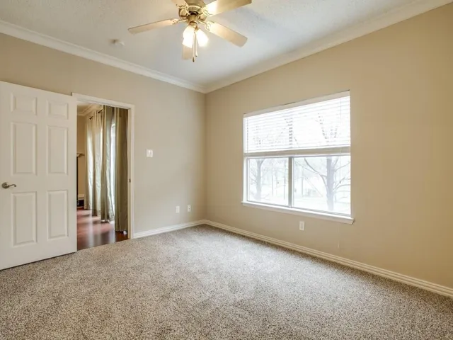 an empty room with windows and chandelier fan