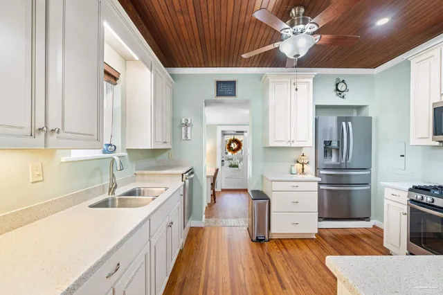 a kitchen with stainless steel appliances a stove a sink dishwasher a refrigerator and cabinets with wooden floor