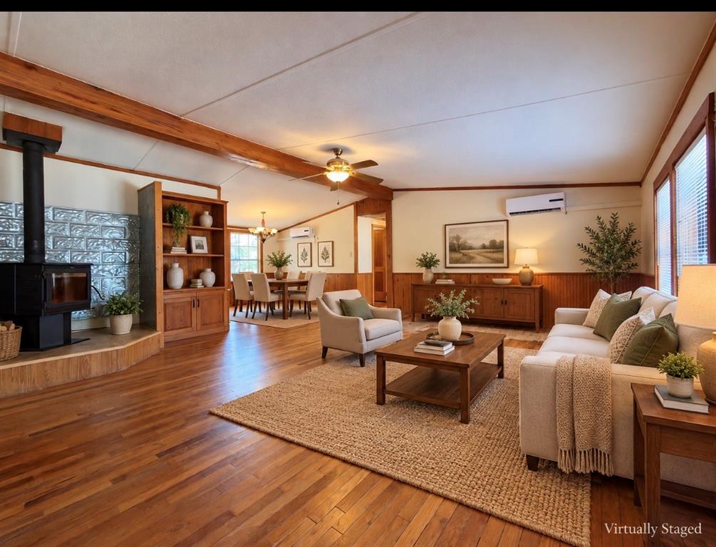 4676 Old Dallas Road Elm Mott, TX 76640 - Photo 3 of 21 Open concept living area featuring wood-finish flooring, exposed wood ceiling beams, and a wood-burning stove with decorative tile surround