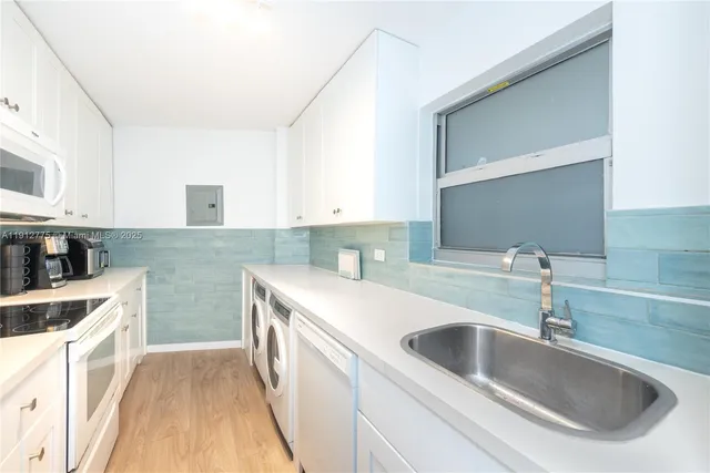 a kitchen with stainless steel appliances a stove a sink and white cabinets