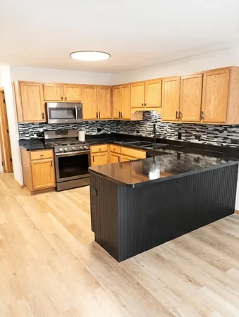 a kitchen with stainless steel appliances granite countertop a stove a sink and a microwave