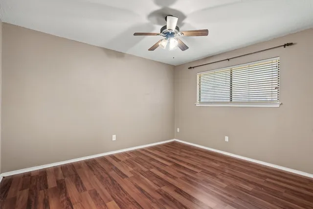a view of a room with wooden floor and a ceiling fan