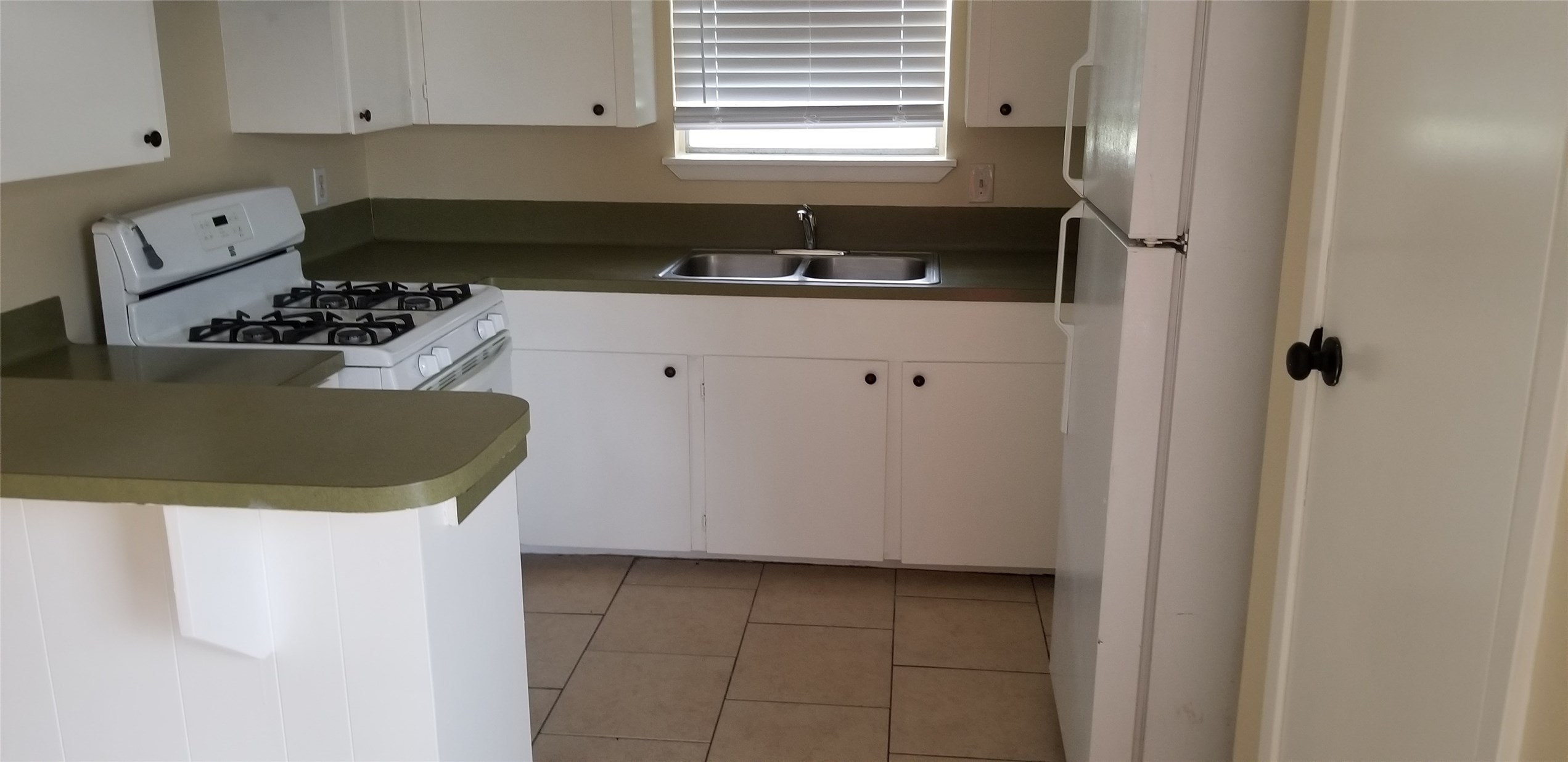2017 West Sidnor Street, Unit 4 Alvin, TX 77511 - Photo 5 of 13 a kitchen with a sink a stove and white cabinets