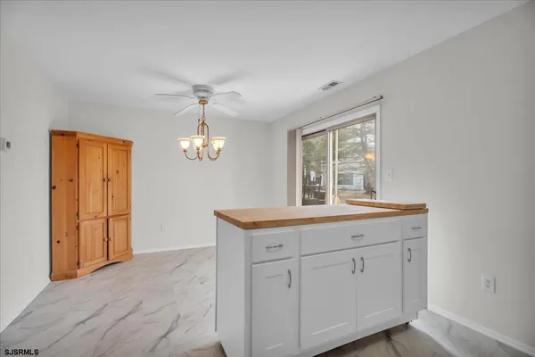 a room with kitchen island granite countertop a stove a sink and a chandelier