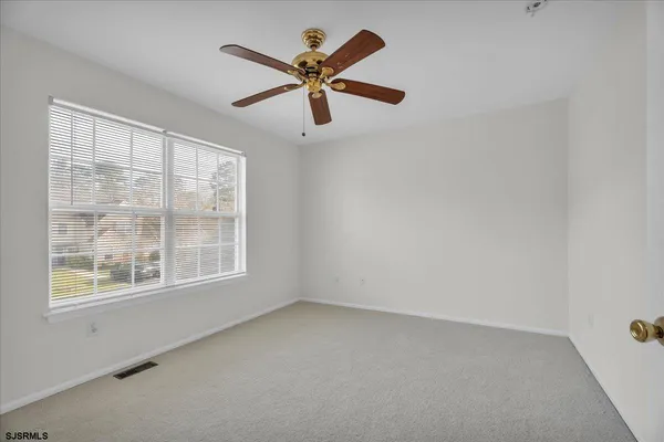 an empty room with windows and fan