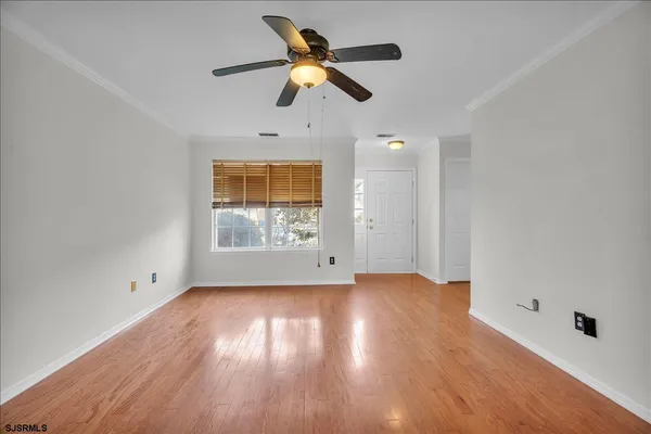 an empty room with wooden floor chandelier fan and windows