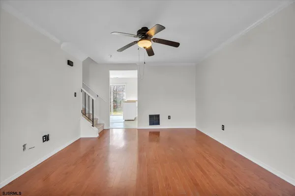 a view of empty room with wooden floor and ceiling fan