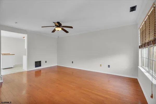 an empty room with chandelier fan and windows
