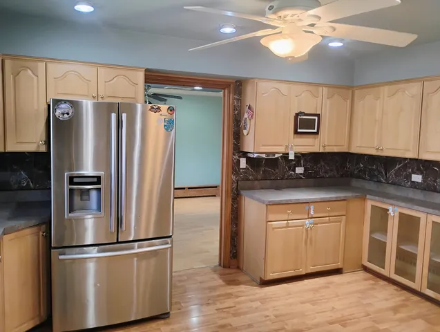 a kitchen with stainless steel appliances granite countertop a refrigerator a sink and white cabinets