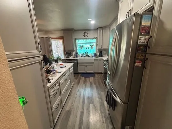 a kitchen with refrigerator a sink and wooden floor