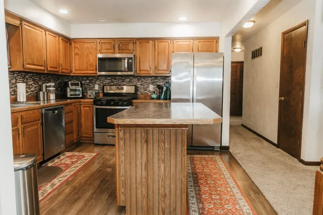 a kitchen with stainless steel appliances granite countertop a refrigerator a stove a sink and a microwave