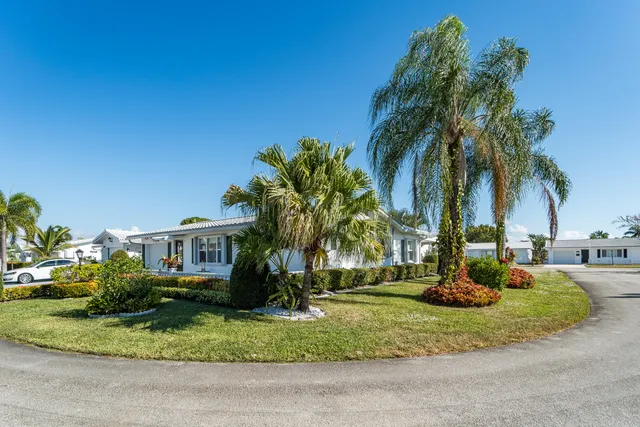 a view of a house with a yard and palm trees