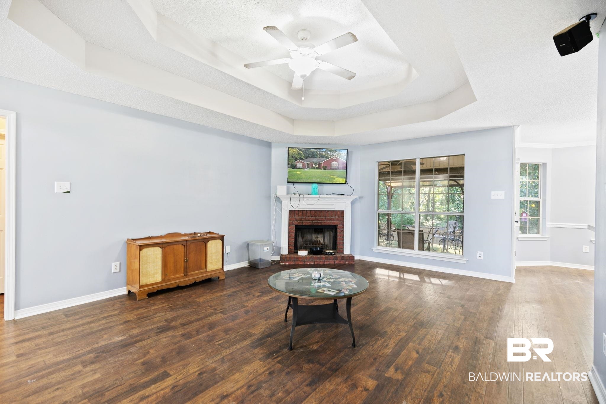 10550 Patrick Avenue Grand Bay, AL 36541 - Photo 10 of 43 Living room featuring a fireplace, wood-type flooring, ceiling fan, a tray ceiling, and a textured ceiling