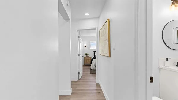 a view of a hallway with wooden floor and a bathroom