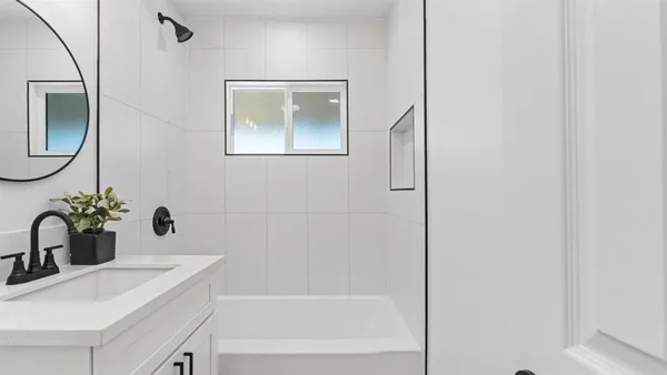 a bathroom with a sink and mirror with bathtub