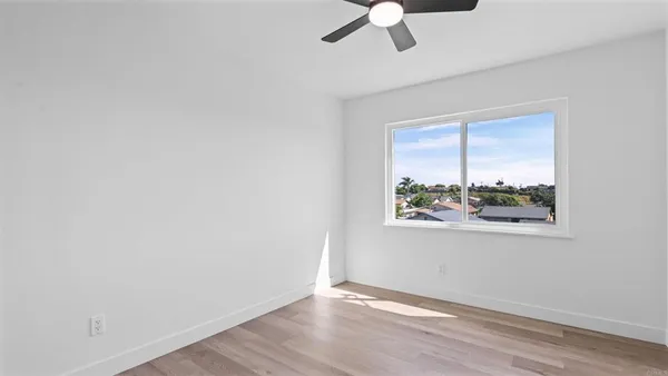 an empty room with a window and a ceiling fan