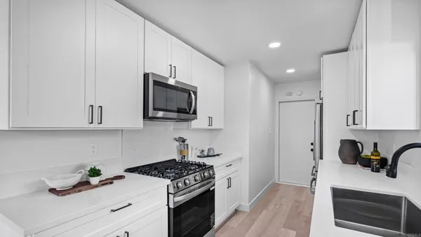 a kitchen with stainless steel appliances white cabinets and a stove top oven