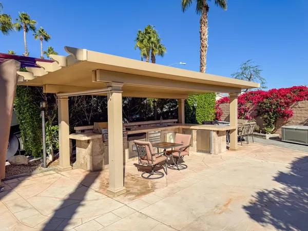 a view of a patio with a table and chairs under an umbrella with potted plants