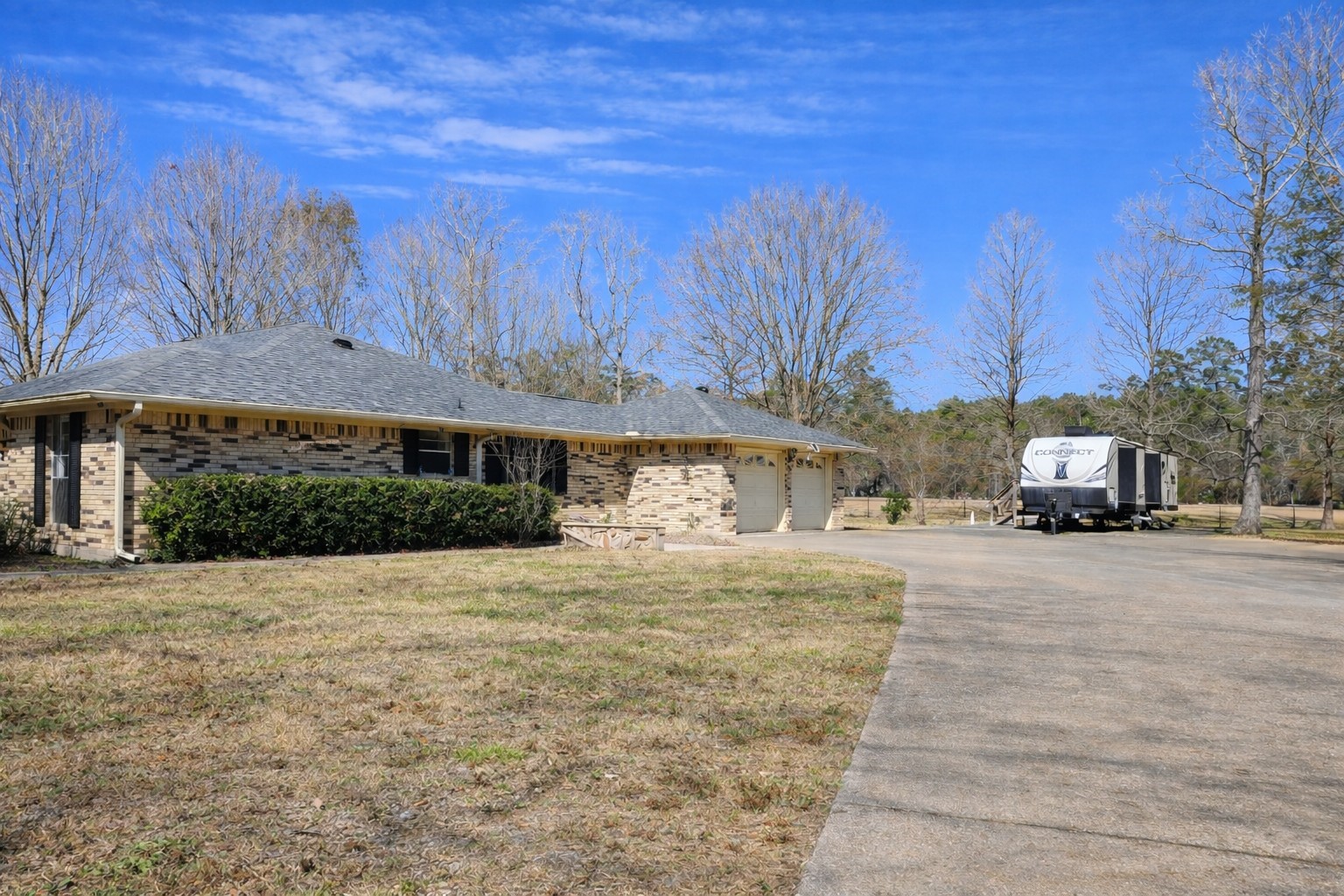 8708 West Fox Road Orange, TX 77632 - Photo 18 of 23 Charming single-story home with a brick exterior, surrounded by a spacious yard and mature trees. Features a wide driveway leading to a two-car garage, offering ample parking space. Ideal for those seeking tranquility and nature.
