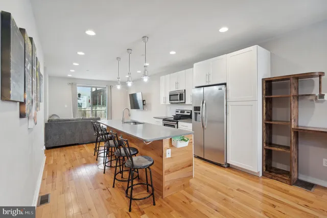 a kitchen with stainless steel appliances a refrigerator a stove a sink dishwasher with a dining table and chairs with wooden floor