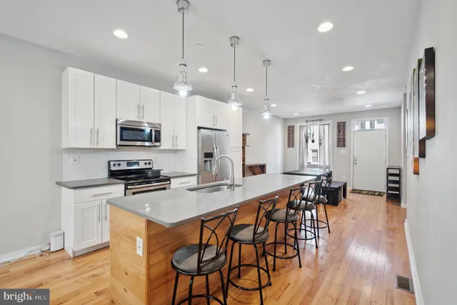 a kitchen with stainless steel appliances kitchen island granite countertop a stove a refrigerator a kitchen island a dining table and chairs with wooden floor