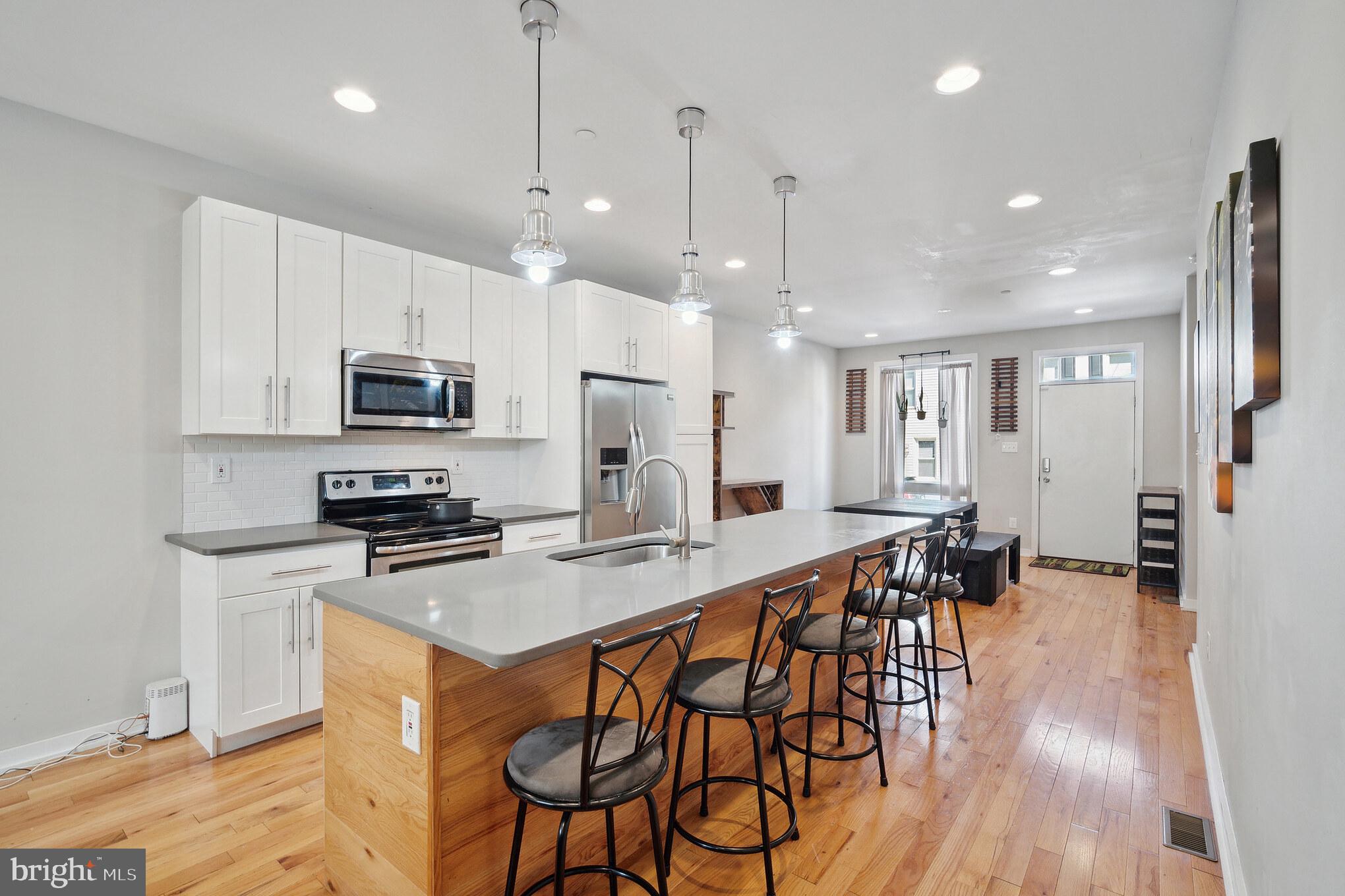 1246 East Fletcher Street Philadelphia, PA 19125 - Photo 7 of 29 a kitchen with stainless steel appliances kitchen island granite countertop a stove a refrigerator a kitchen island a dining table and chairs with wooden floor