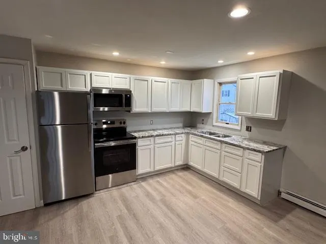 a kitchen with granite countertop a refrigerator and a stove top oven